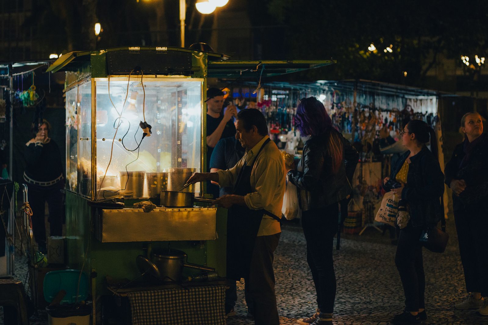 A small night-market food cart serving locals on a city sidewalk