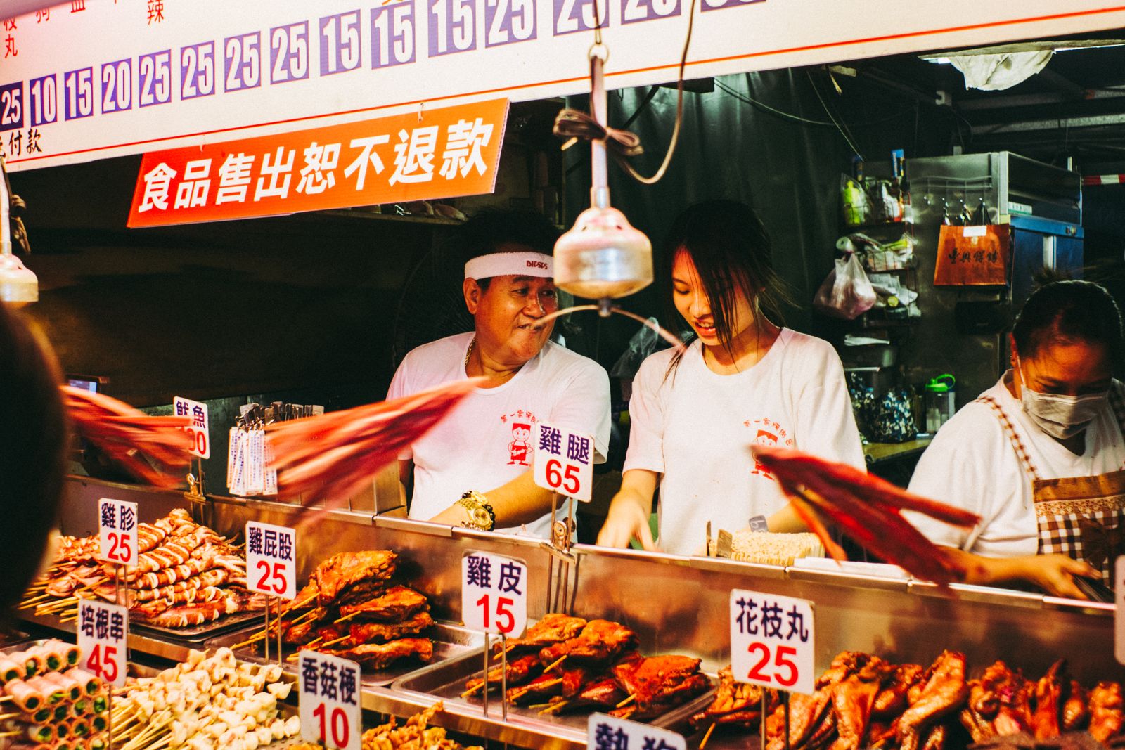 Vendors serving grilled street food at a crowded local market stall